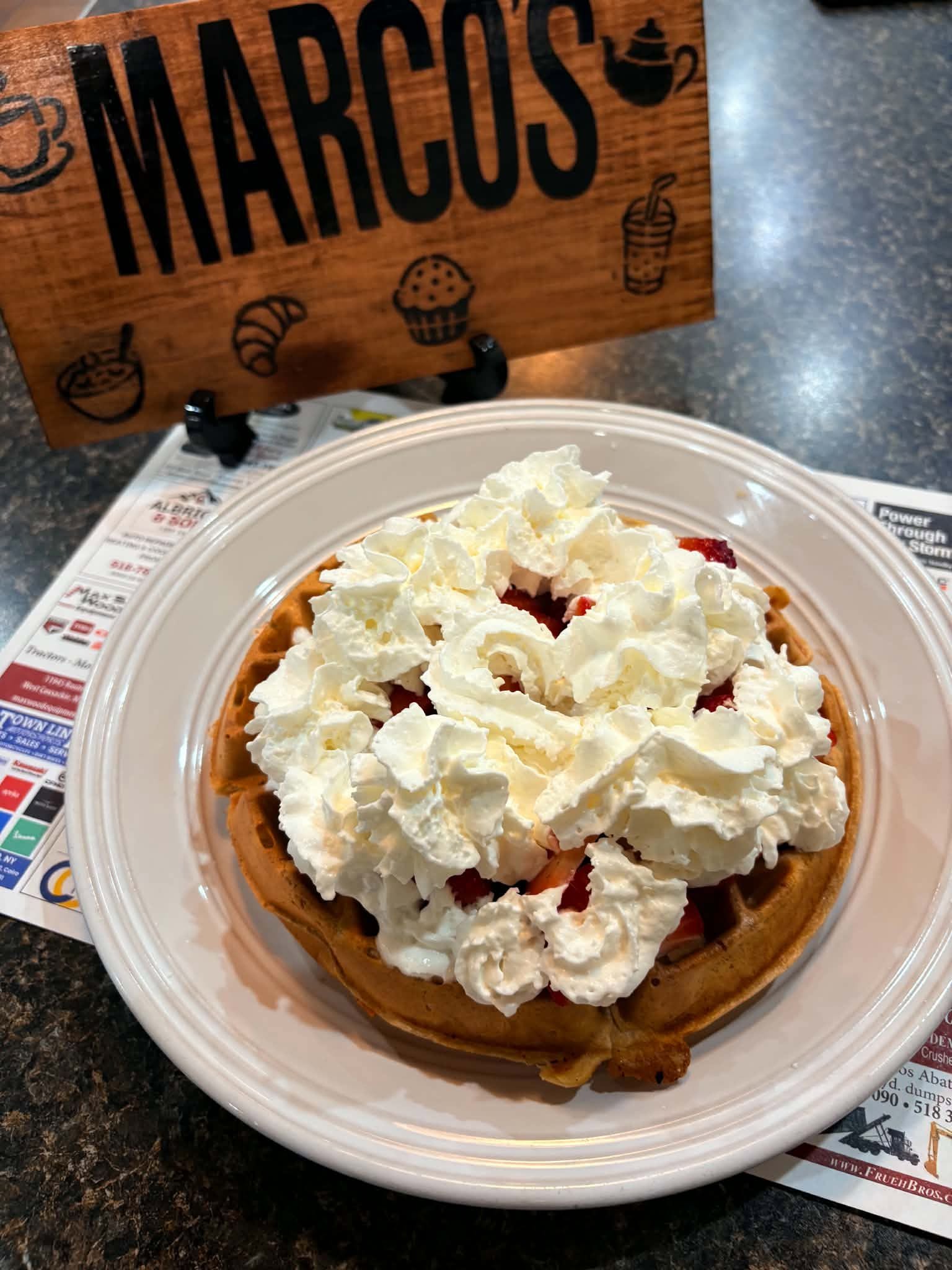 A strawberry waffle topped with whipped cream, served at Marco’s Diner
